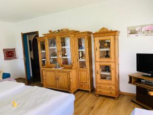 1 dormitorio con armarios de madera, TV y cama en Appartementhaus Sonne en Millstatt