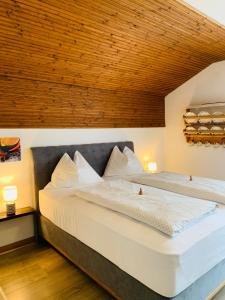 two beds in a bedroom with a wooden ceiling at Appartementhaus Sonne in Millstatt
