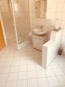 ein weißes Badezimmer mit Dusche und Waschbecken in der Unterkunft Alt-Emder Bürgerhaus in Emden + 37 Fotos