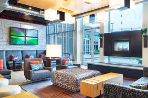 a lobby with a tv and a couch and chairs at Aloft Hotel Plano in Plano