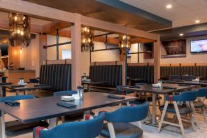 Delta Hotels by Marriott Kalamazoo Conference Center في كالامازو: مطعم بطاولات خشبية وكراسي زرقاء