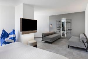 a hotel room with a bed and a chair and a television at Moxy La Ciotat in La Ciotat