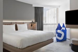a bedroom with a large bed and a tv at Moxy La Ciotat in La Ciotat