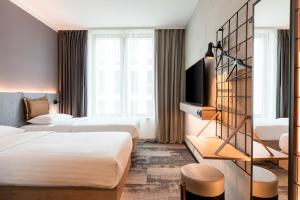 ein Hotelzimmer mit 2 Betten und einem TV in der Unterkunft Moxy Wuerzburg in Würzburg