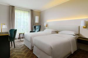 a hotel room with three beds and a table and chairs at Sheraton Offenbach Hotel in Offenbach