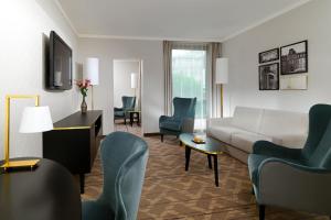 فندق شيراتون أوفنباخ في أوفنباخ: غرفة معيشة مع أريكة وكراسي