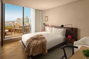 バルセロナにあるThe Barcelona EDITIONのベッドと大きな窓が備わるホテルルームです。