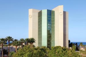 a tall glass building with palm trees in front of it at Sheraton Jeddah Hotel in Jeddah