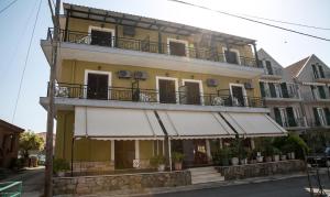 a yellow building with a balcony on the side of it at Petania Hotel & Apartments in Lixouri