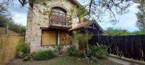 a stone house with a fence in front of it at Wayra Waka in Villa Giardino