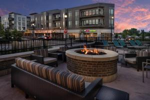 eine Feuerstelle auf einer Terrasse mit Stühlen und einem Gebäude in der Unterkunft TownePlace Suites by Marriott Milwaukee Oak Creek in Oak Creek