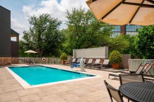 una piscina con sillas, una mesa y una sombrilla en Four Points by Sheraton Dallas Arlington Entertainment District, en Arlington