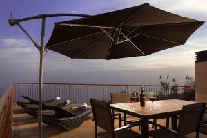- une table avec un parasol et deux verres de vin dans l'établissement KING´S HOUSE (Sea View and Indoor BBQ), à Estreito da Calheta