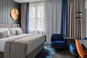 a hotel room with a bed and a blue chair at Garamond a Tribute Portfolio Hotel in Kraków