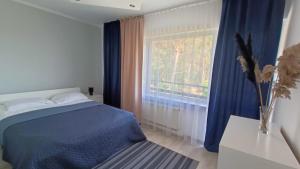 sypialnia z niebieskim łóżkiem i oknem w obiekcie Noclegi na Piaskach w mieście Krynica Morska