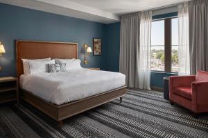 Habitación de hotel con cama y silla roja en The Memphian a Tribute Portfolio Hotel en Memphis
