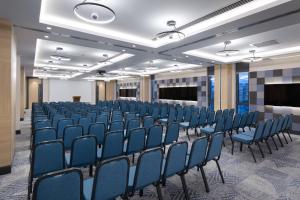 una sala de conferencias con sillas azules y una pantalla en Courtyard by Marriott Chisinau en Chisináu