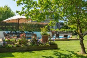 a garden with chairs and an umbrella and flowers at Luccombe Villa Holiday Apartments in Shanklin