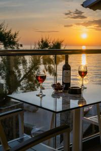 twee glazen wijn zittend op een tafel met zonsondergang bij Black Rocks Luxury Seafront Beach Suite in Agios Gordios