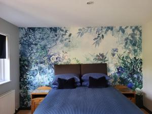 um quarto com uma cama azul e papel de parede floral em The Garden Rooms at Tannery House em Bakewell