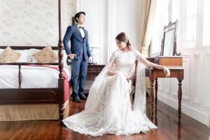 a bride and groom standing in front of a bed at The Hermitage, A Tribute Portfolio Hotel, Jakarta in Jakarta