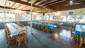 uma sala de jantar com mesas, cadeiras e janelas em Tropicana Motor Inn em Cowes