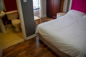 a bedroom with a bed and a toilet and a sink at Paddy's Palace Belfast in Belfast