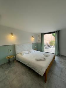 een slaapkamer met een groot bed en een groot raam bij Appartement Zuria T3 in Bonifacio
