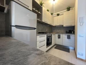 una cucina con mobili bianchi e un frigorifero di La StorHouse nuovo appartamento sul corso di Porto Recanati a Porto Recanati