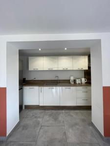 een lege keuken met witte kasten en een tegelvloer bij Appartement Zuria T3 in Bonifacio