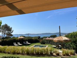 a resort with a pool and chairs and an umbrella at La Bastide du Soleil in Sainte-Maxime