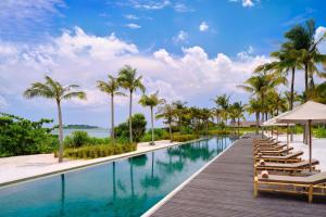 uma piscina de beiral infinito do resort com espreguiçadeiras e palmeiras em Sheraton Belitung Resort em Tanjungbinga