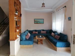 a living room with a blue couch and a table at Maison Belle Dune in Saïdia