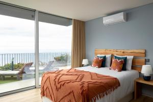 a bedroom with a large bed and a balcony at King´s Paradise (Heated Pool and Sea View) in Estreito da Calheta +16 photos