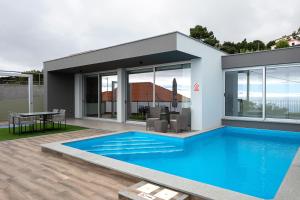a house with a swimming pool in front of it at King´s Paradise (Heated Pool and Sea View) in Estreito da Calheta