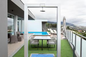 a balcony with a table and chairs and a swimming pool at King´s Paradise (Heated Pool and Sea View) in Estreito da Calheta
