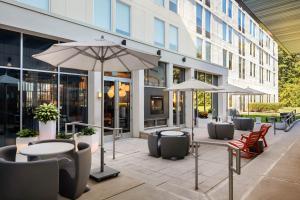 a patio with tables and umbrellas in front of a building at Aloft BWI Baltimore Washington International Airport in Linthicum Heights