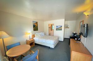 1 dormitorio con cama, mesa y TV en Alger Falls Motel, en Munising