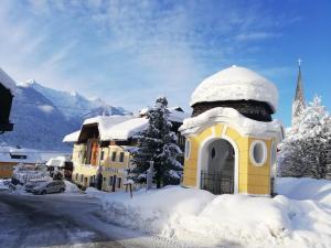 a yellow building covered in snow next to a street at Gasthof zur Schmiede in Berg im Drautal