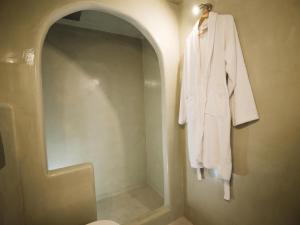 a white robe hanging on a wall in a bathroom at Anthemis Suites in Imerovigli