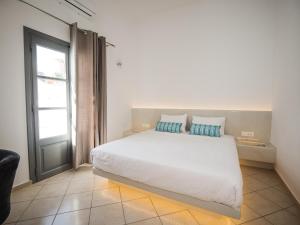 a bedroom with a large white bed with blue pillows at Anthemis Suites in Imerovigli