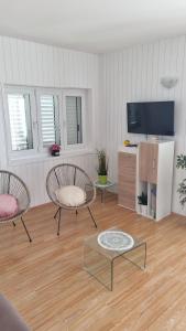 uma sala de estar com 2 cadeiras e uma televisão de ecrã plano em Villa Silvana Brown em Marusici 