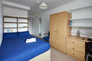 a bedroom with a blue bed and a wooden cabinet at Goldsmid House, Victoria in London