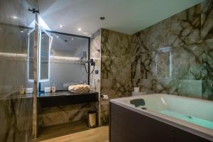 een badkamer met een bad en een glazen douche bij Black Rocks Luxury Seafront Beach Suite in Agios Gordios