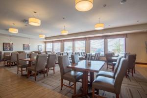Four Points by Sheraton Saskatoon في ساسكاتون: غرفة طعام مع طاولات وكراسي ونوافذ