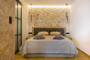 a bedroom with a bed with a stone wall at Black Rocks Luxury Seafront Beach Suite in Agios Gordios