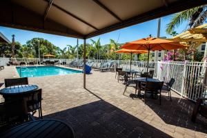 eine Terrasse mit Tischen und Sonnenschirmen sowie einem Pool in der Unterkunft TownePlace Suites by Marriott Boynton Beach in Boynton Beach