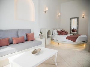 un soggiorno con un letto e un divano di Anthemis Suites a Imerovigli