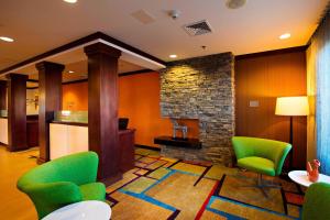 a lobby with green chairs and a stone fireplace at Fairfield Inn and Suites by Marriott Tifton in Tifton