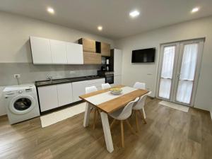 uma cozinha com uma mesa de madeira e armários brancos em Le Pavoncelle em Valledoria